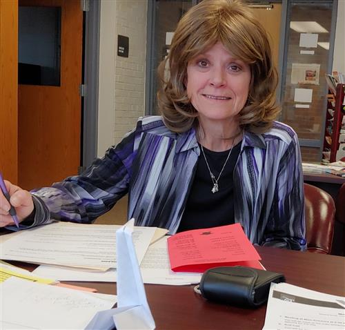 Photo of Connie Cox light brown bob, wearing a colorful striped blouse with a black top and silver necklace 