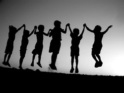 Silhouettes of children holding hands and jumping 