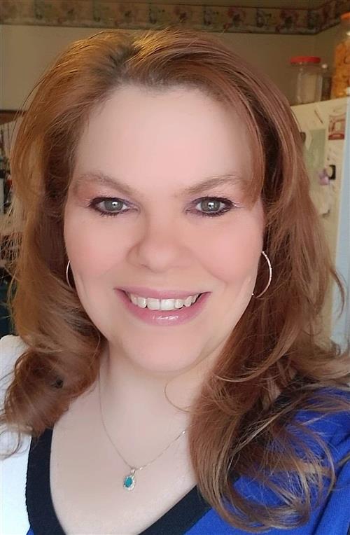 Headshot photo of Malissa Smith with red hair, hoop earrings and blue, white, and black top 